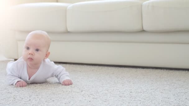 Concepto de hijos y paternidad. Lindo bebé feliz está acostado en la alfombra
 - Imágenes, Vídeo