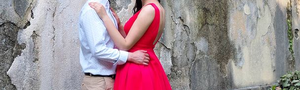 A beautiful elegant couple in love, hugs in the park, romantic date. Stylish man and woman in red dress - Фото, зображення