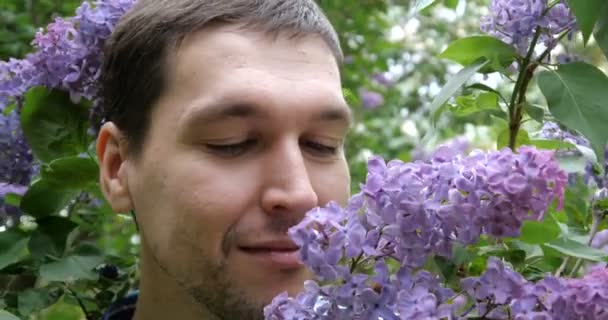 4K - A young guy sniffs lilac and winks in slow motion - Footage, Video