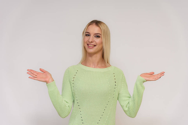 Photo portrait of a beautiful blonde girl talking on a white background with different emotions. She is standing right in front of the camera, smiling and looking happy. - Zdjęcie, obraz