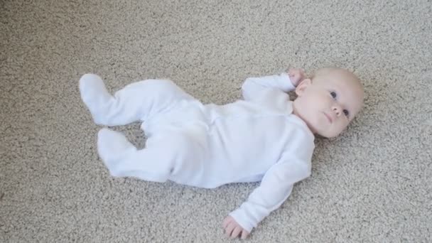 Koncepció, a gyermekek és a szülői. Aranyos boldog baba, a szőnyegen fekve - Felvétel, videó