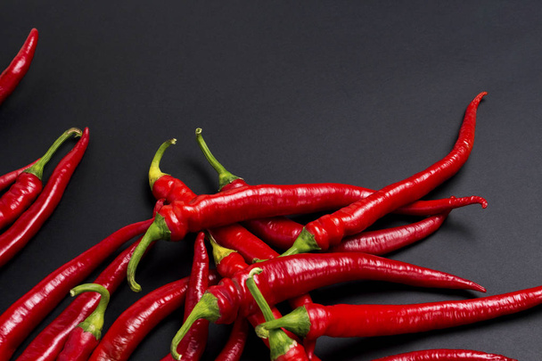 Rode hete chili pepers op een zwarte achtergrond. - Foto, afbeelding