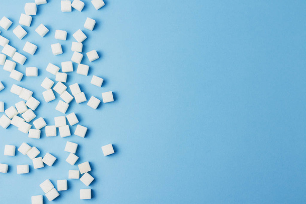 A lot of sugar cubes on a blue background - Фото, изображение