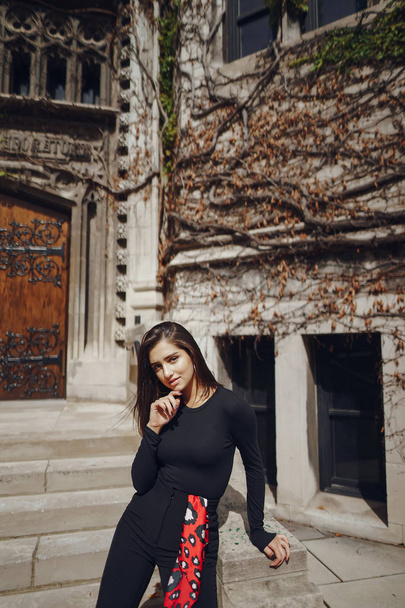 stylish brunette standing next to the entance to a building - Zdjęcie, obraz