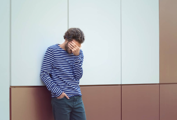 Hombre joven estresado cerca de la pared al aire libre
 - Foto, imagen