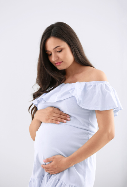 Kaunis raskaana oleva nainen valoisalla taustalla - Valokuva, kuva