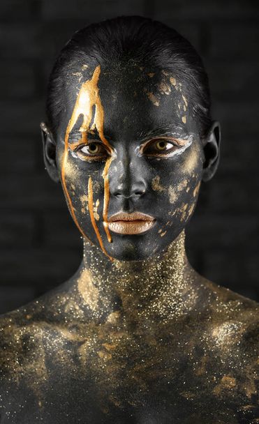 美しいです女性とともに黒と金色の塗料で彼女の体に暗い背景 - 写真・画像