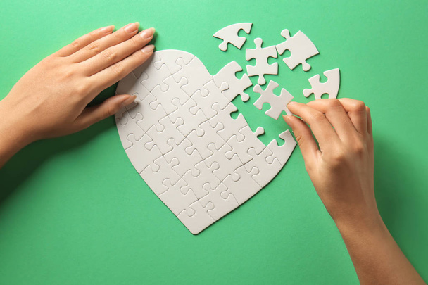 Woman doing jigsaw puzzle on color background - Photo, Image