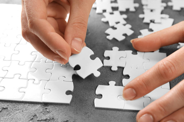 Woman doing jigsaw puzzle on table, closeup - Foto, afbeelding