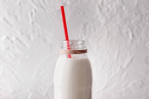 Fles van de lekkere melk met stro op witte achtergrond - Foto, afbeelding