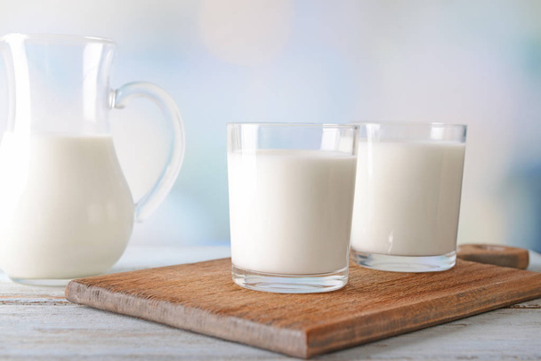 Composição com copos e jarro de leite saboroso em mesa de madeira
 - Foto, Imagem