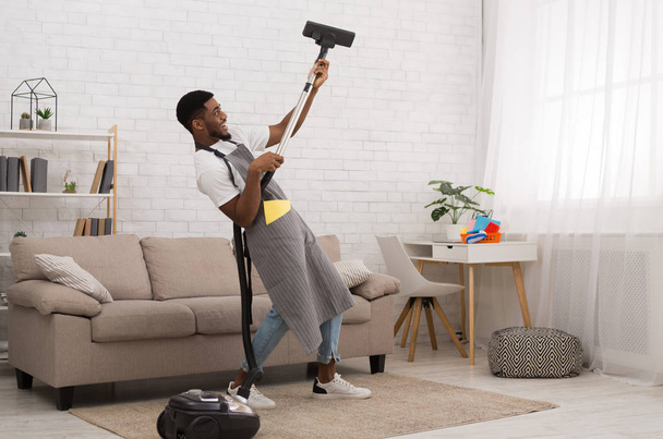 Young man cleaning house with vacuum cleaner - Photo, Image