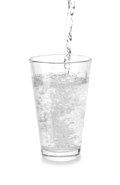 Gieten van mineraalwater in glas op witte achtergrond - Foto, afbeelding