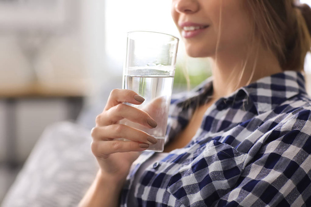 Beautiful young woman drinking water at home, closeup - Foto, Imagem