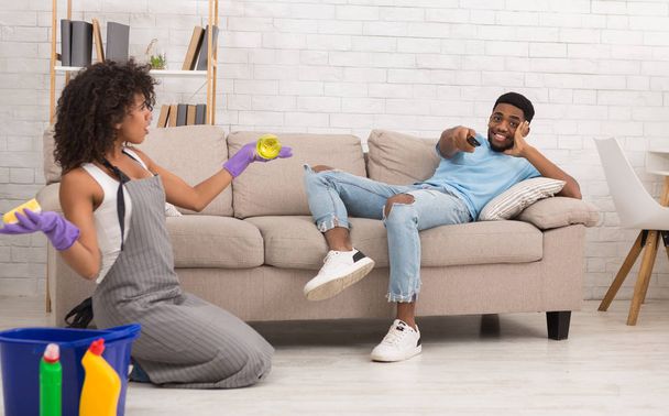 Mulher limpando casa enquanto seu namorado descansando no sofá
 - Foto, Imagem