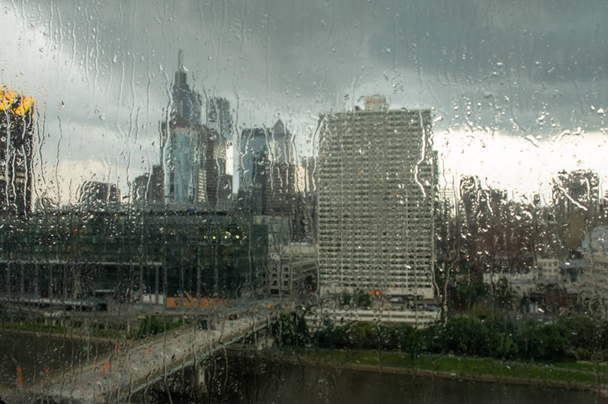 Katse sateen läpi putoaa lasiin ikkunasta ulos kaupungin ylle.
. - Valokuva, kuva
