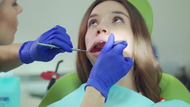 Zbliżenie na ręce dentysta, badając pacjenta zęby gardłowe - Materiał filmowy, wideo
