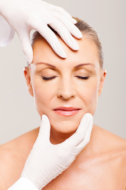 plastic surgeon checking middle aged womans face - Photo, Image