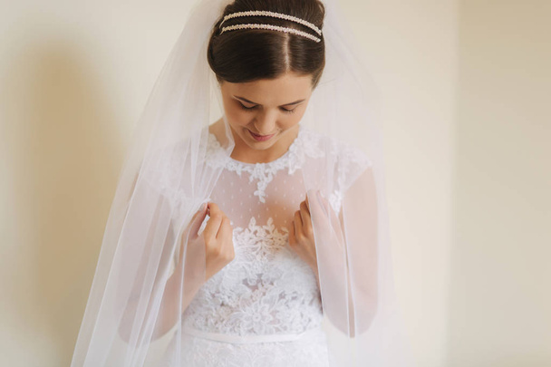 Beautiful bride stand near the window in white wedding dress. Charming lady - Fotoğraf, Görsel
