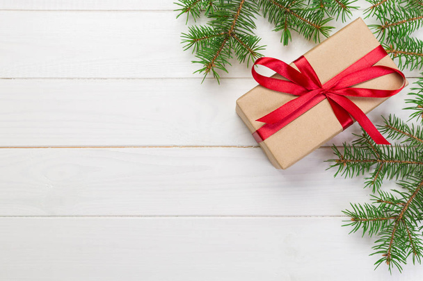 Χριστουγεννιάτικο φόντο χριστουγεννιάτικο δώρο με κλαδιά έλατου σε ξύλινο λευκό φόντο με αντίγραφο χώρος επίπεδη lay, κάτοψη. - Φωτογραφία, εικόνα