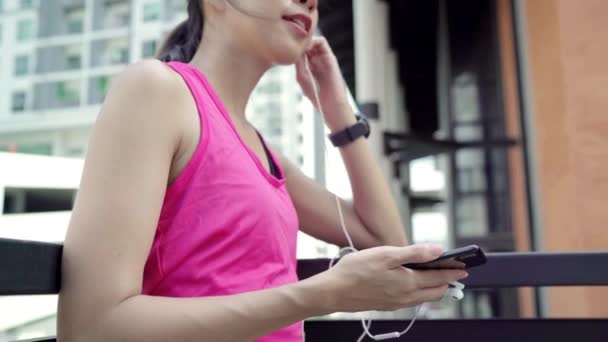 Healthy beautiful young Asian Athlete woman using smartphone for listen to music while running in urban city. Lifestyle women exercise in the city concept. - Video