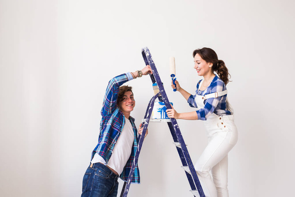 Family, renovation, happiness and redecoration concept - young family doing repair, painting walls together and laughing - Fotoğraf, Görsel