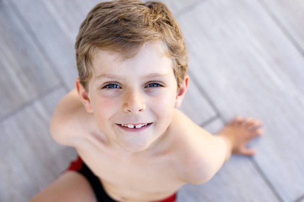 Retrato de menino pequeno sorridente bonito no dia ensolarado quente do verão. Um miúdo feliz a olhar para a câmara. Criança adorável com cabelos loiros e olhos azuis
 - Foto, Imagem
