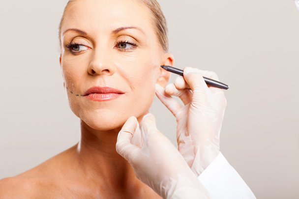 doctor correcting senior woman face - Foto, Imagen