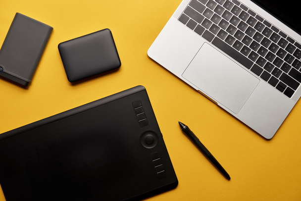 top view of different graphic designer gadgets on yellow surface - Photo, Image