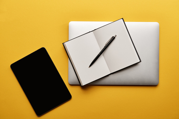 vista superior de aparelhos sem fio com notebook em branco na superfície amarela
 - Foto, Imagem