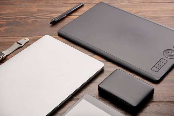 close-up shot of various wireless devices and graphics tablet on wooden desk - Photo, Image