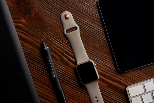 Smartwatch mit drahtloser Tastatur, Digital- und Grafik-Tablet auf Holztisch - Foto, Bild