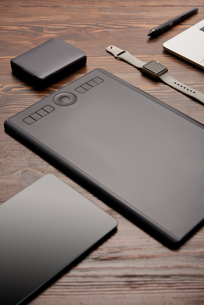 Close-up shot van professionele grafisch tablet met verschillende gadgets op houten tafel - Foto, afbeelding