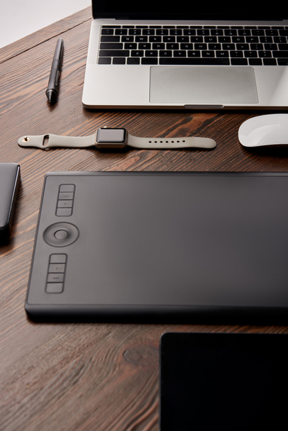 close-up de gráficos profissionais tablet com vários gadgets na mesa de madeira
 - Foto, Imagem