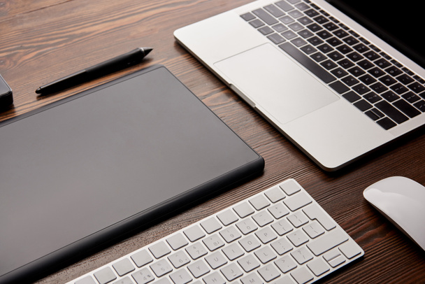 close-up shot of laptop with wireless keyboard and graphics tablet on wooden table - Foto, Imagem