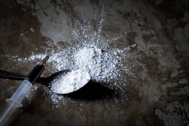 Drug syringe and cooked heroin in spoon on floor - Фото, зображення