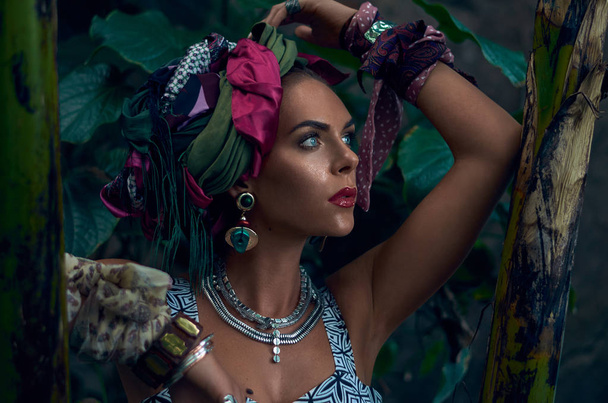 Fotomodel in tulband poseren buitenshuis met jungle achtergrond - Foto, afbeelding