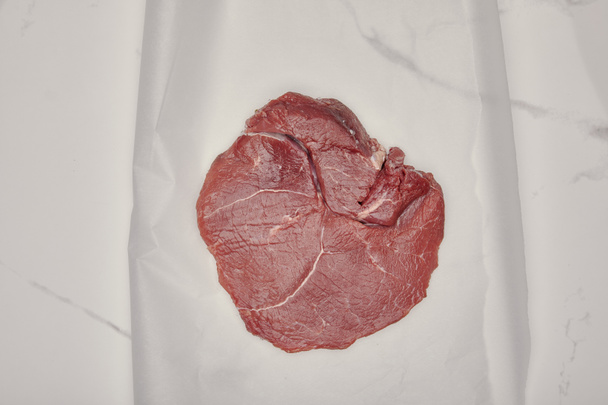 vista superior de carne fresca crua sobre papel de cozinha sobre fundo branco
 - Foto, Imagem