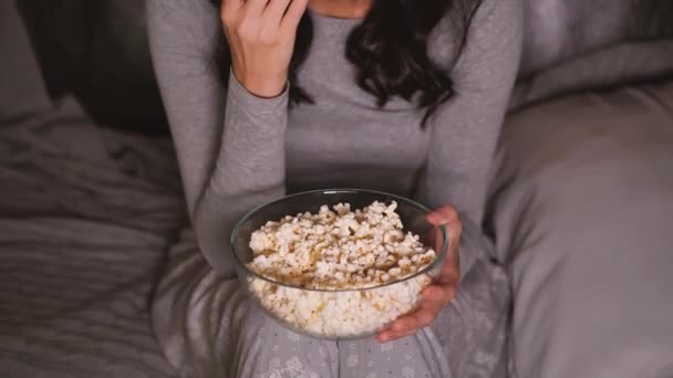 Pretty woman watching something funny on tv at home. Eating popcorn. - Felvétel, videó