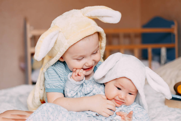 ウサギの耳笑顔を身に着けている幼児の男の子と赤ちゃんの女の子の肖像画. - 写真・画像