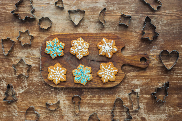 flat lay with christmas cookies on cutting board and cookie cutters around on wooden surface - Photo, Image