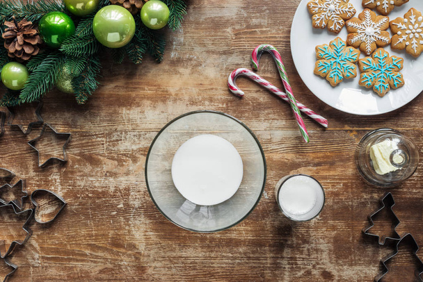 flat lay with milk in bowl, christmas decorative wreath and baked cookies on wooden surface - 写真・画像