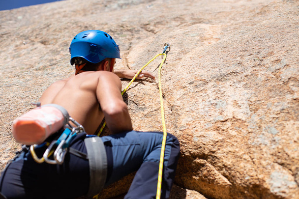 Nahaufnahme eines hemdlosen männlichen Bergsteigers beim Klettern einer Bergwand an einem sonnigen Tag  - Foto, Bild