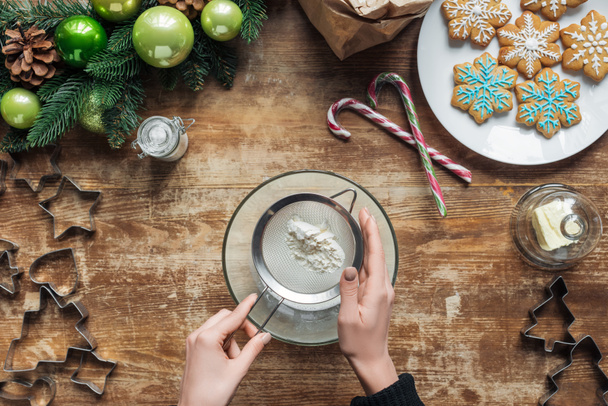 bijgesneden schot van vrouw maken van deeg voor christmas cookies bakkerij op houten tafelblad met decoratieve krans - Foto, afbeelding