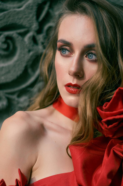 Πορτρέτο της μια ελκυστική γυναίκα με κόκκινο χρώμα. Φωτογραφία μόδας. - Φωτογραφία, εικόνα