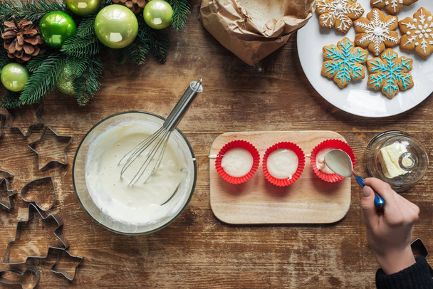 partial view of woman pouring dough into baking forms on wooden tabletop, christmas baking concept - Foto, Imagem