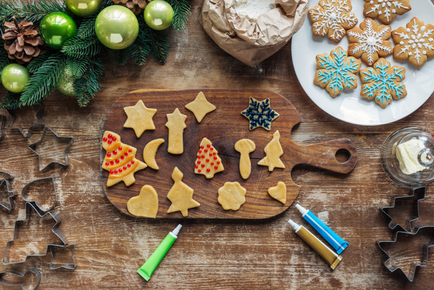 top view of arrangement of raw dough, food grade ink for christmas cookies bakery and and christmas wreath on wooden tabletop - Foto, afbeelding