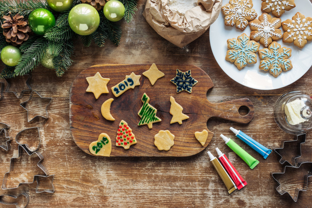 top view of arrangement of raw dough, food grade ink for christmas cookies bakery and and christmas wreath on wooden tabletop - Valokuva, kuva