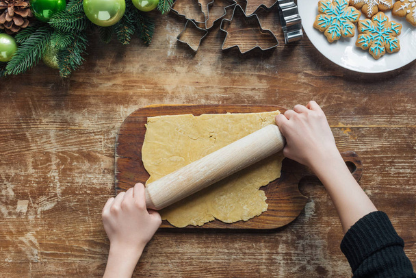 tiro cortado de massa de rolamento mulher com rolo de pino para biscoitos de Natal em mesa de madeira
 - Foto, Imagem