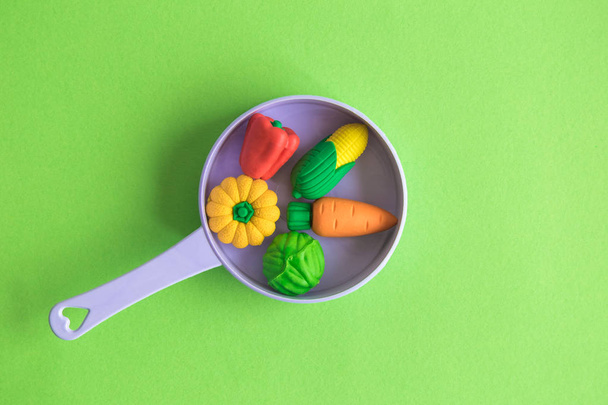 Rubber vegetables in plastic pan on pastel green background minimal creative concept. - Фото, зображення